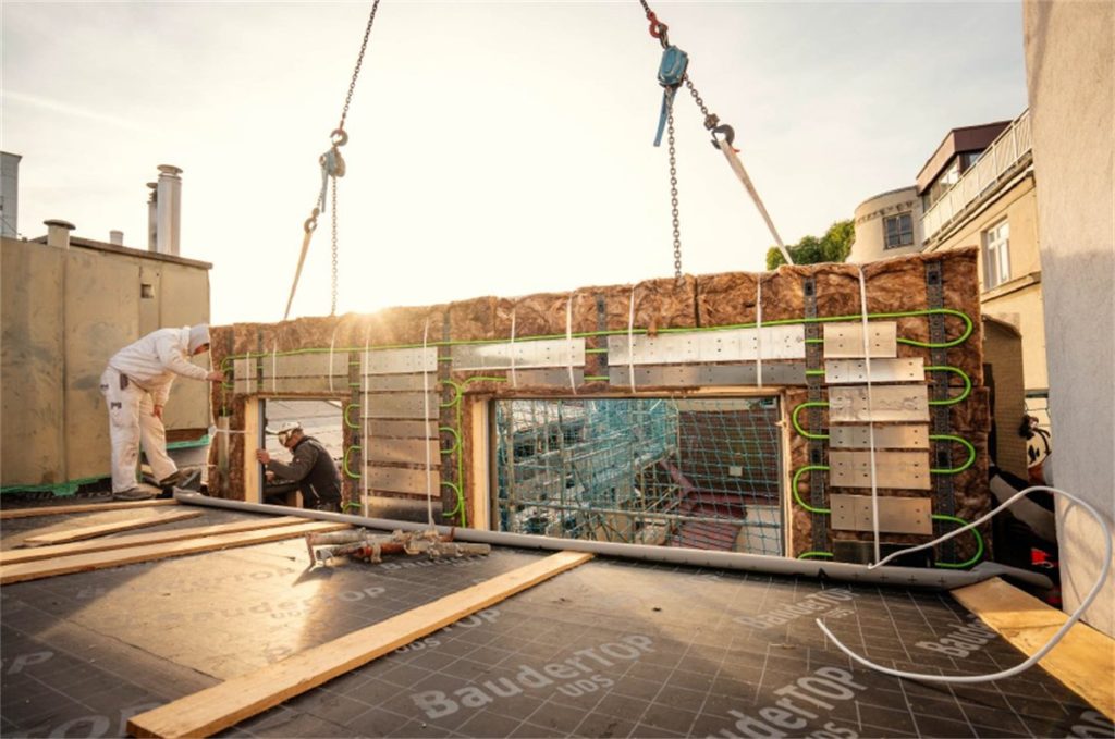 Kranmontage eines vorgefertigten Fassadenelements mit integrierten CEPA-Energieleitungen an einem Bestandsgebaeude